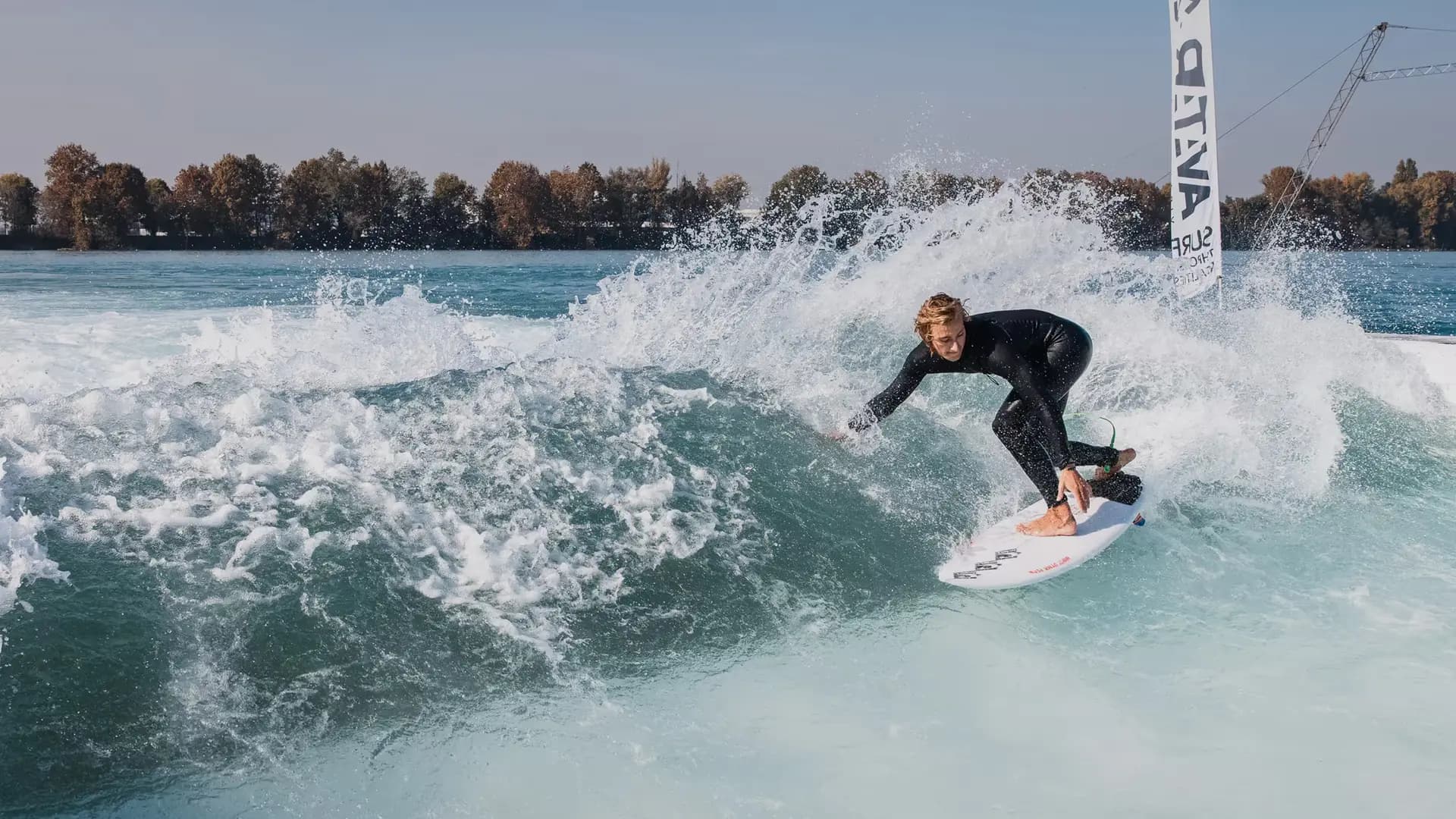 A surfer carving the face of a standing wave, spray arcing behind the board